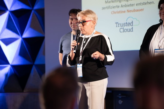 Eine Person spricht auf einer Bühne in ein Mikrofon